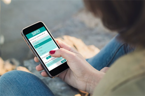 Photograph of a woman's hand taking an online survey on her phone.