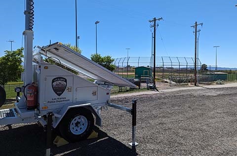 Image of the North Mesa ball field on a sunny day. A LAPD surveillance trailer is in the foreground in the left hand corner.